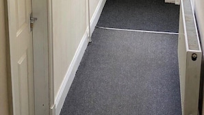A hallway with a door, a bulletin board, a fire exit sign, and a fire alarm. - House 2 bedrooms Sleeps 4 with Parking (Bolton)