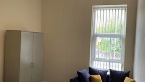 A room with a bed, a sofa, a wardrobe, and a window with blinds. - House 2 bedrooms Sleeps 4 with Parking (Bolton)