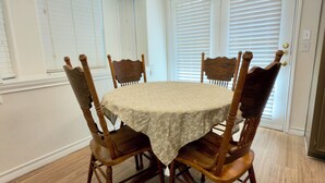 A dining area with a round table, four wooden chairs, and a light-colored tablecloth. - The Oak - Spacious 2BR - 2BA •
Sleeps 6 • Wi-Fi (Mission)
