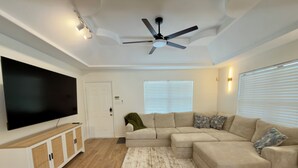 A living room with a sectional sofa, a flat-screen TV, a ceiling fan, and a wooden floor. - The Oak - Spacious 2BR - 2BA •
Sleeps 6 • Wi-Fi (Mission)