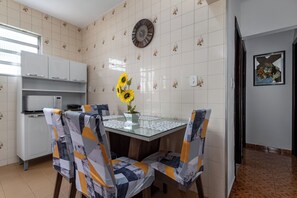 Eine Küche mit Esstisch, Stühlen, einer Uhr und einem Wandbild.