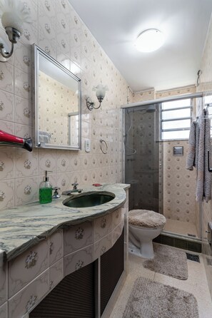 Ein Badezimmer mit Dusche, Toilette und Waschbecken, mit gemusterten Fliesen und einem Spiegel.