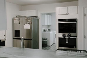 Eine moderne Küche mit Edelstahlgeräten, darunter ein Kühlschrank, ein Backofen und eine Mikrowelle.