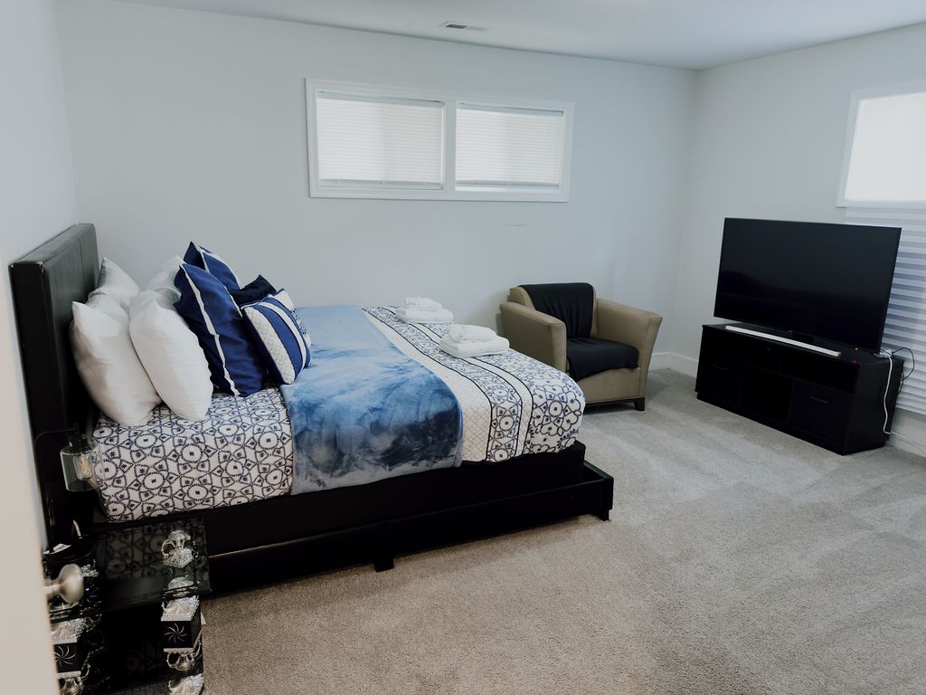 A bedroom with a bed, a television, a chair, and a window.