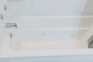 Une baignoire blanche avec deux robinets et un drain.