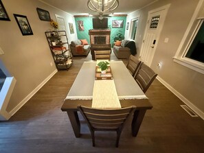 Un comedor con una mesa larga, sillas, una araña y una chimenea.