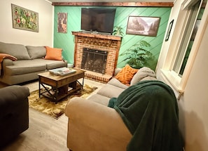 A living room with a fireplace, sofa, and television.