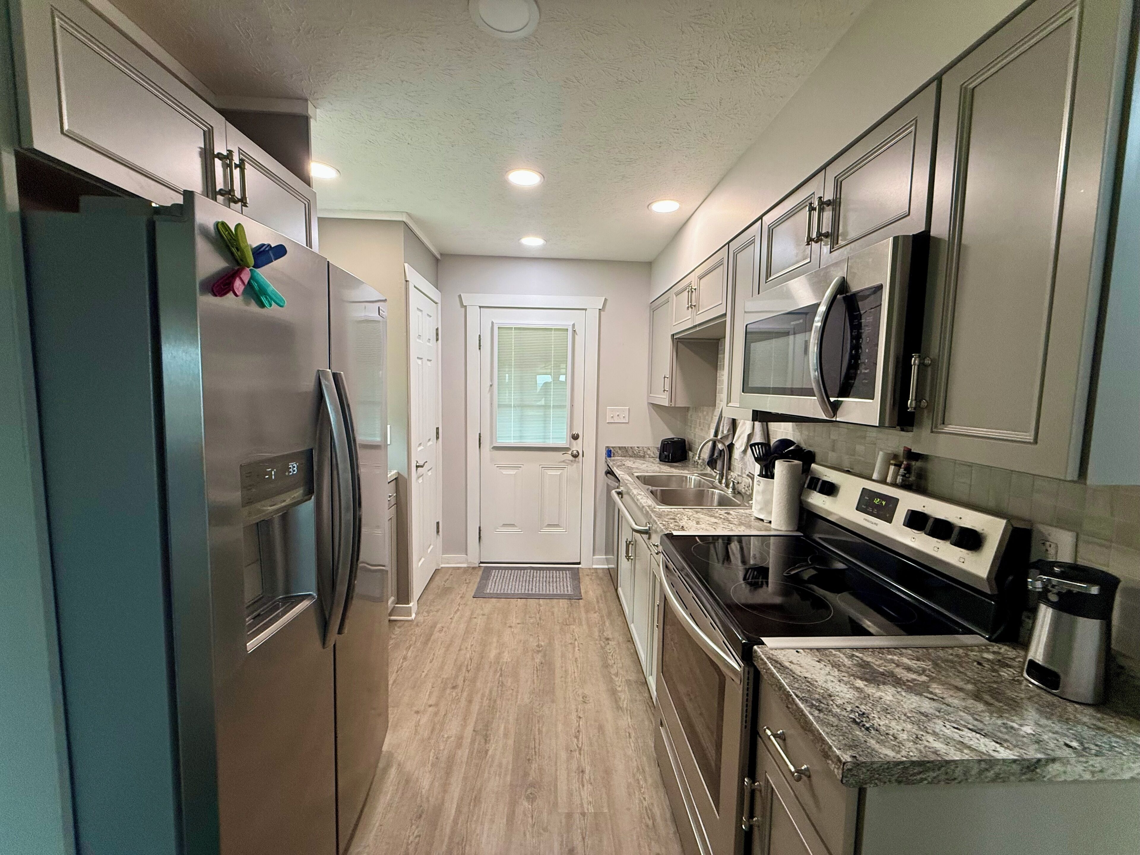 A modern kitchen with stainless steel appliances, a microwave, and a large window.