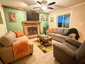 Una sala de estar con chimenea, un sofá, una mesa de centro y una televisión.