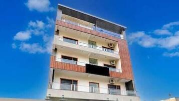Un immeuble à plusieurs étages doté de balcons, un ciel dégagé et un drapeau.