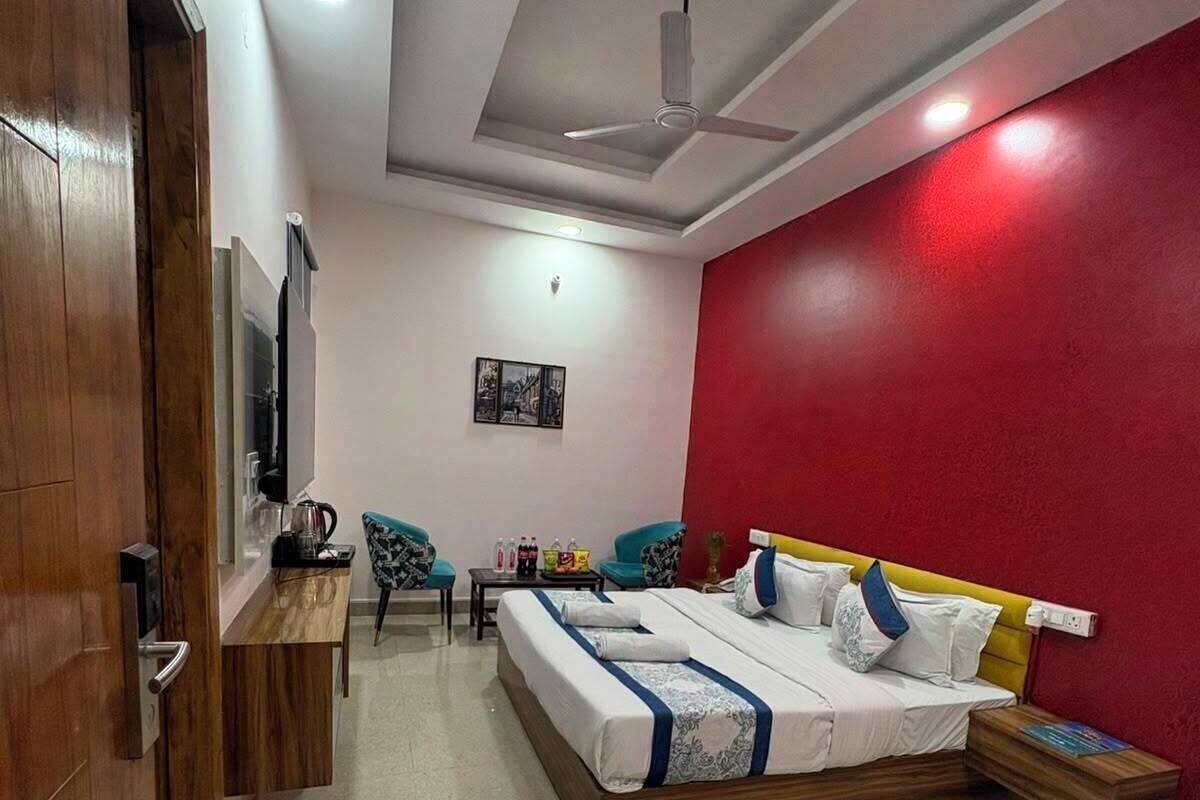 Un dormitorio con cama, escritorio, silla y pared de acento roja.