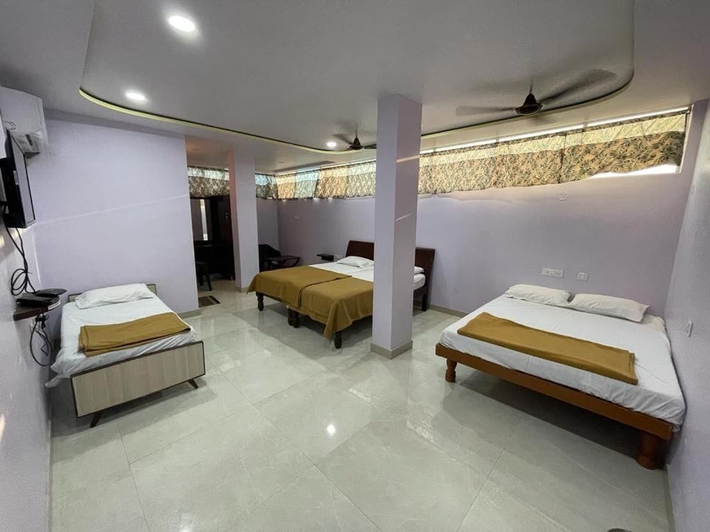 Habitación de hotel con tres camas, ventilador de techo y pared con diseño.