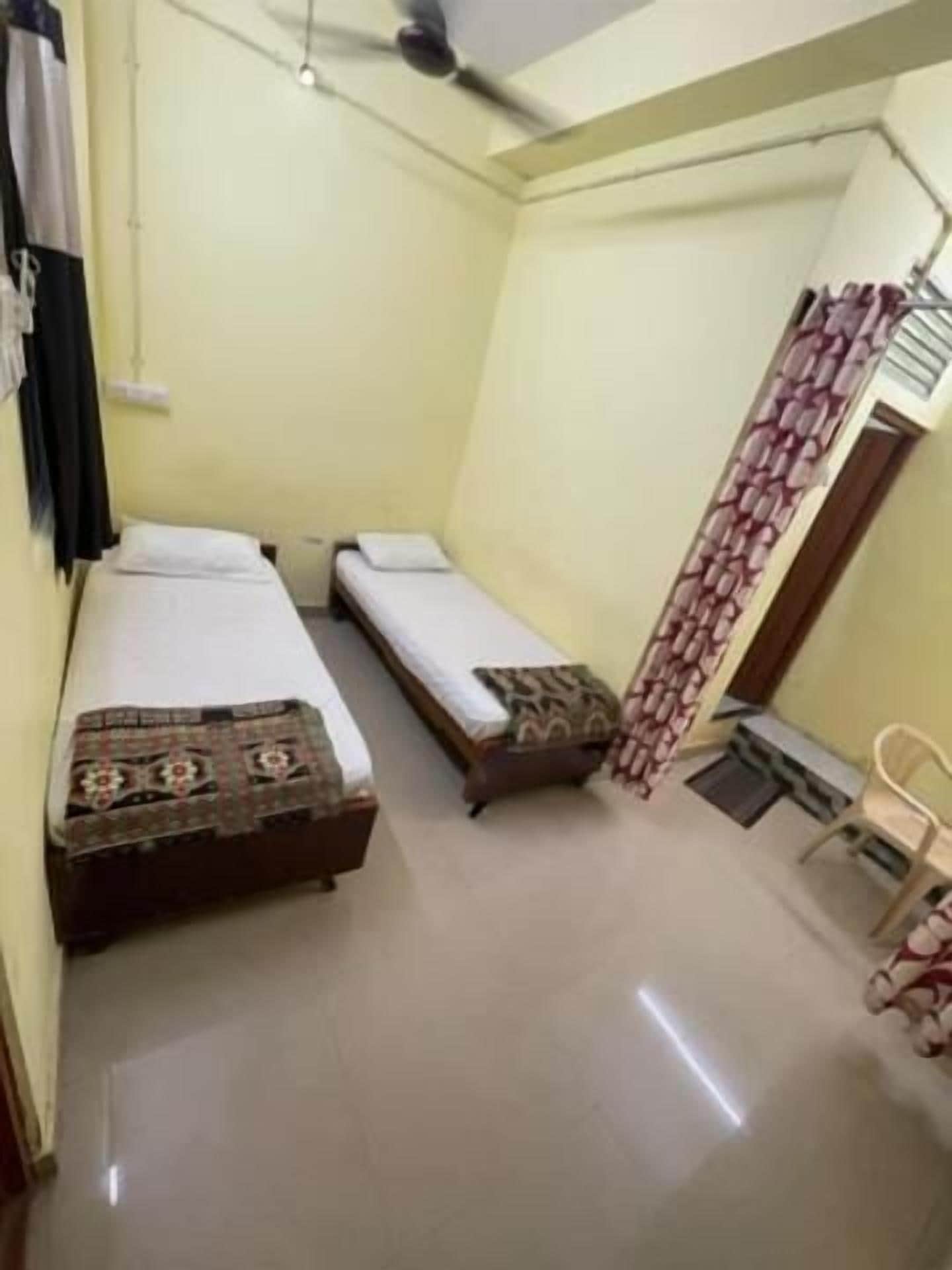 A small, compact room with two single beds, a desk, and a chair.