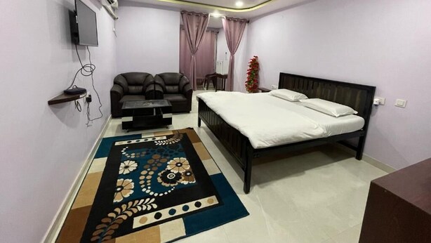Ein Schlafzimmer mit Bett, Sofa, Fernseher und Deckenventilator.