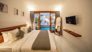 Habitación de hotel con cama, televisión, vista a la piscina y área de comedor.