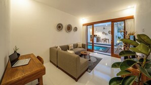 Una sala moderna con un sofá, una mesa de madera con una computadora portátil y un comedor con sillas.