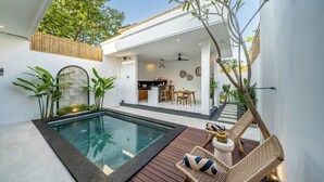 Una casa moderna con piscina, terraza de madera y zona de comedor.