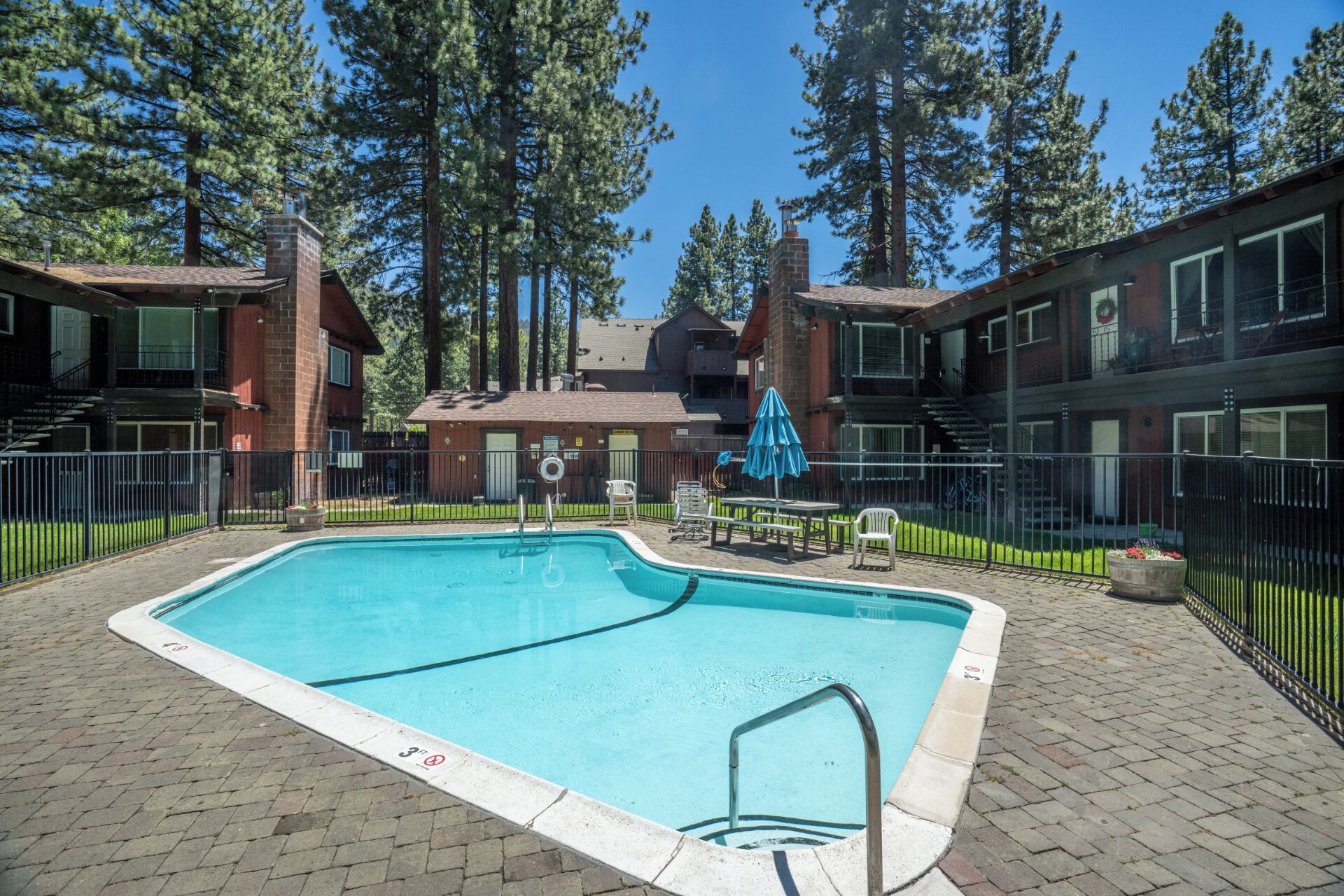 A swimming pool with a brick border, surrounded by a brick patio.