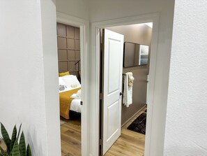 Ein Hotelzimmer mit Bett, Nachttisch, Spiegel und einer Tür zu einem Badezimmer.