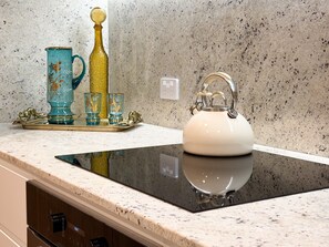 Eine Küche mit einer Granit-Arbeitsplatte, einem weißen Wasserkocher und dekorativem Glaswaren-Sortiment.