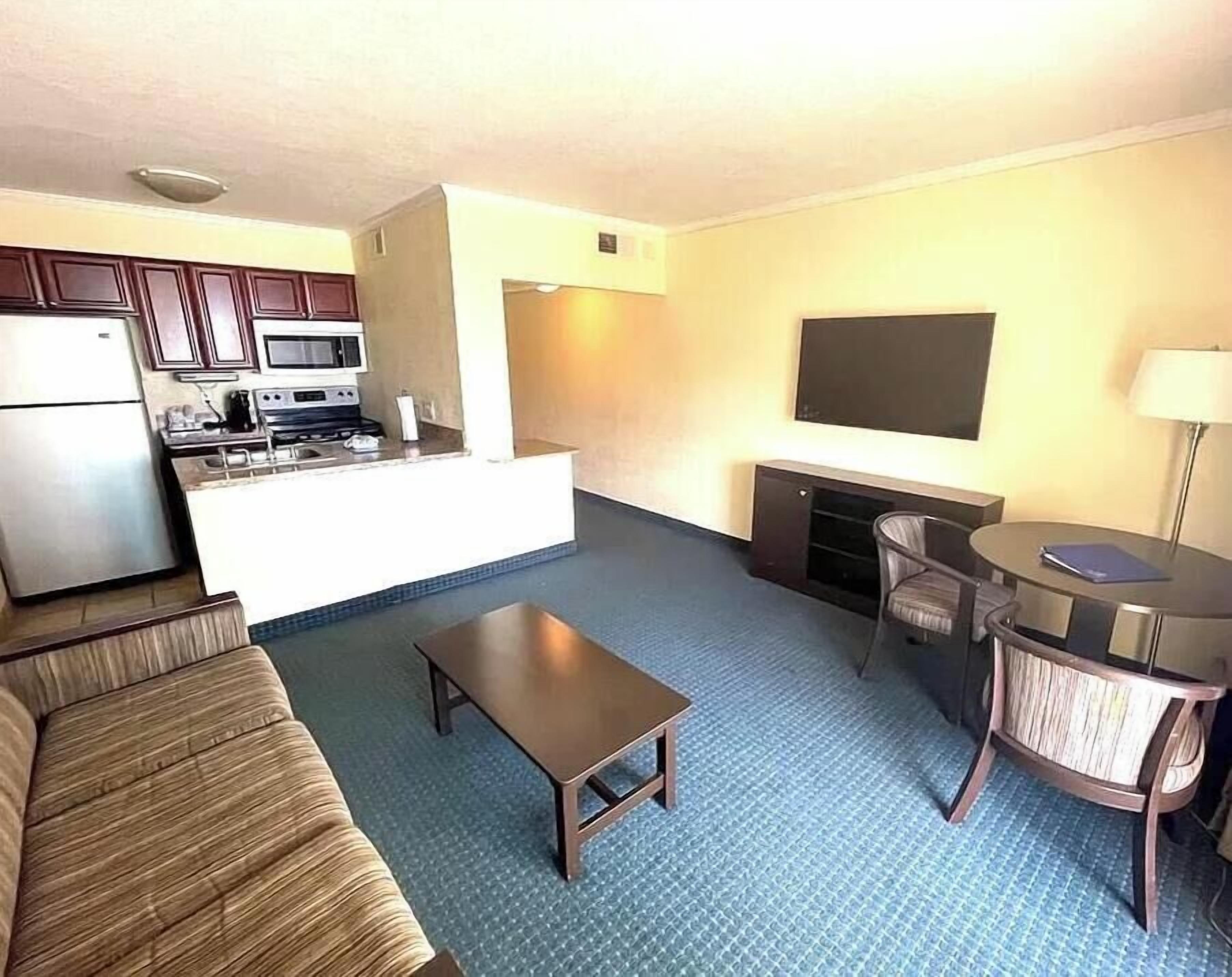 Un espacio habitable compacto con kitchenette, un sofá, una mesa de centro, un televisor y una pequeña zona de comedor.