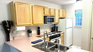A kitchen with wooden cabinets, a stainless steel sink, a microwave, and a refrigerator. - Relax & Unwind~Cozy 1bed/1bath Condo with Beautiful Pond & Golf Views (Branson)