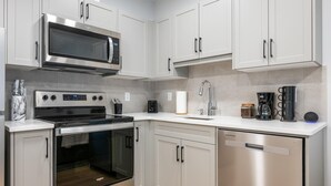 Una cocina moderna con electrodomésticos de acero inoxidable, armarios blancos, horno integrado y lavavajillas.