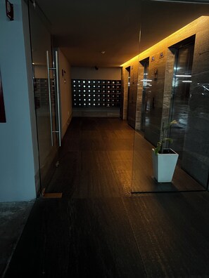 Ein Flur mit modernem Design, inklusive eines Glaselevators, einer Pflanze und einer Wand mit kreisförmigen Mustern.