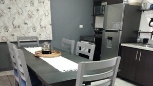 Un comedor con una mesa, sillas, refrigerador y microondas.