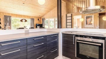 A modern kitchen with dark cabinetry, a stainless steel oven, and a large window.