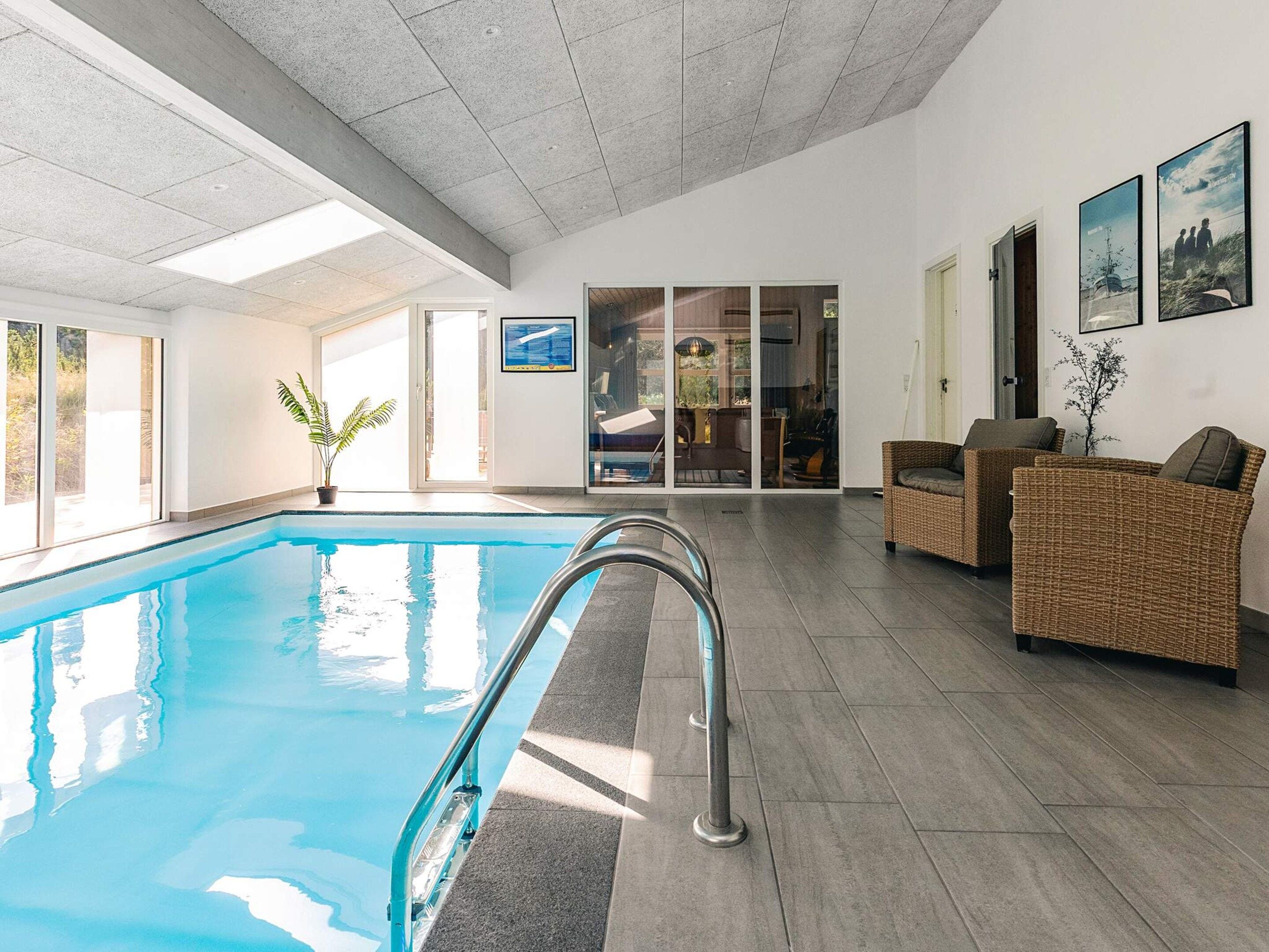 En swimmingpool med krystalklar himmel, en fletsofa og et indrammet billede på væggen.