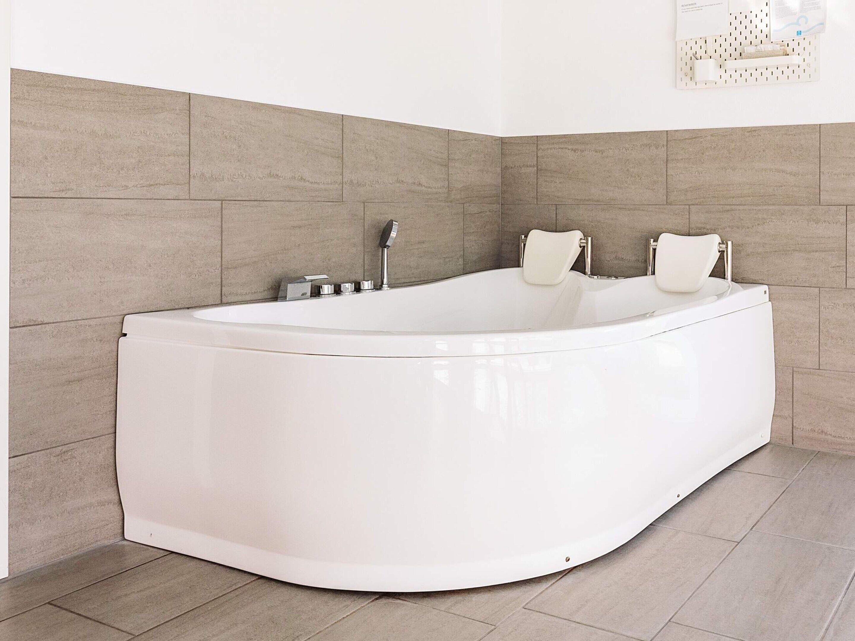Een moderne badkamer met een vrijstaand bad, een handdouche en een handdoekrek.