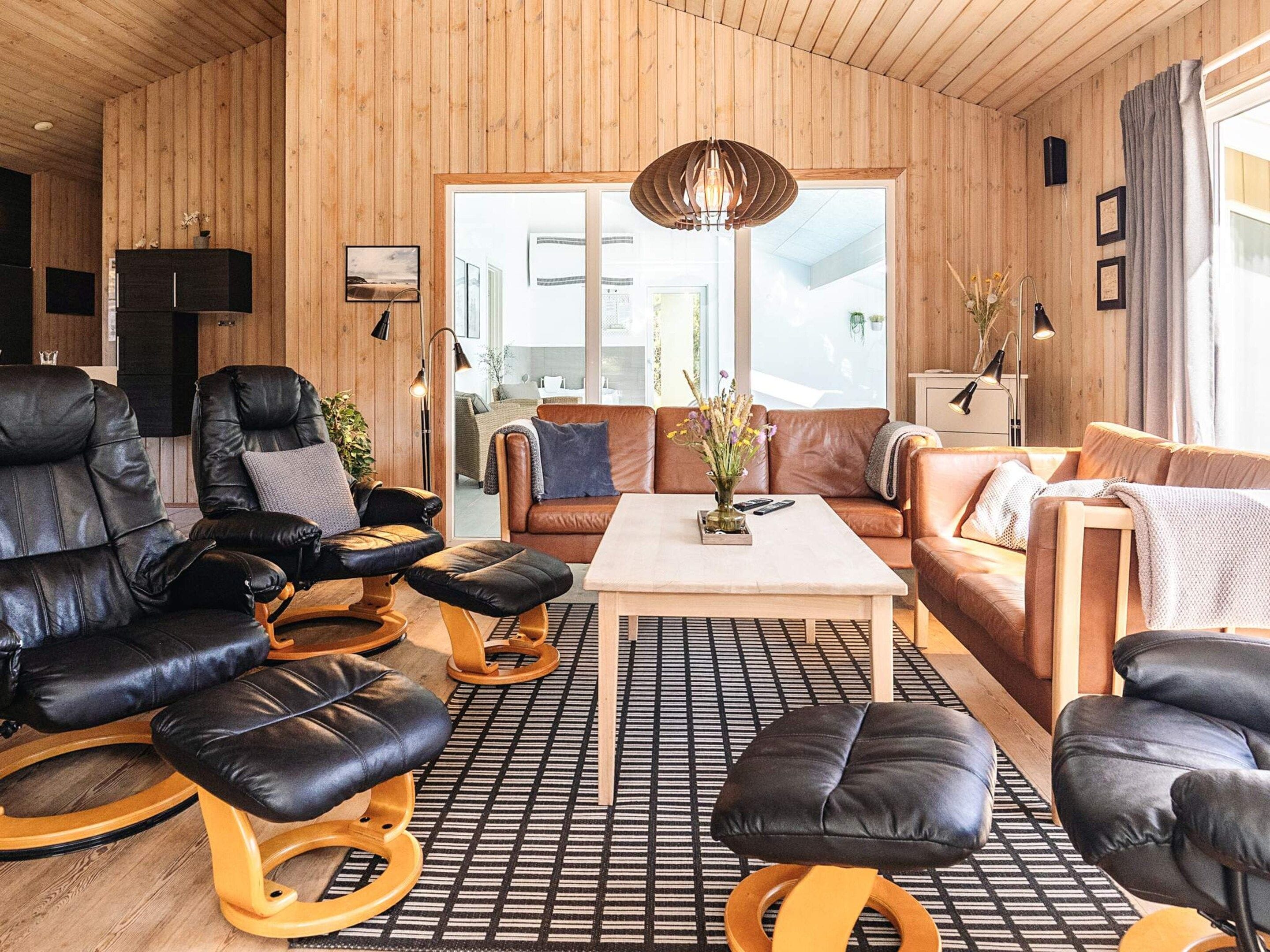 A modern living room with leather sofas, a coffee table, and a patterned rug.