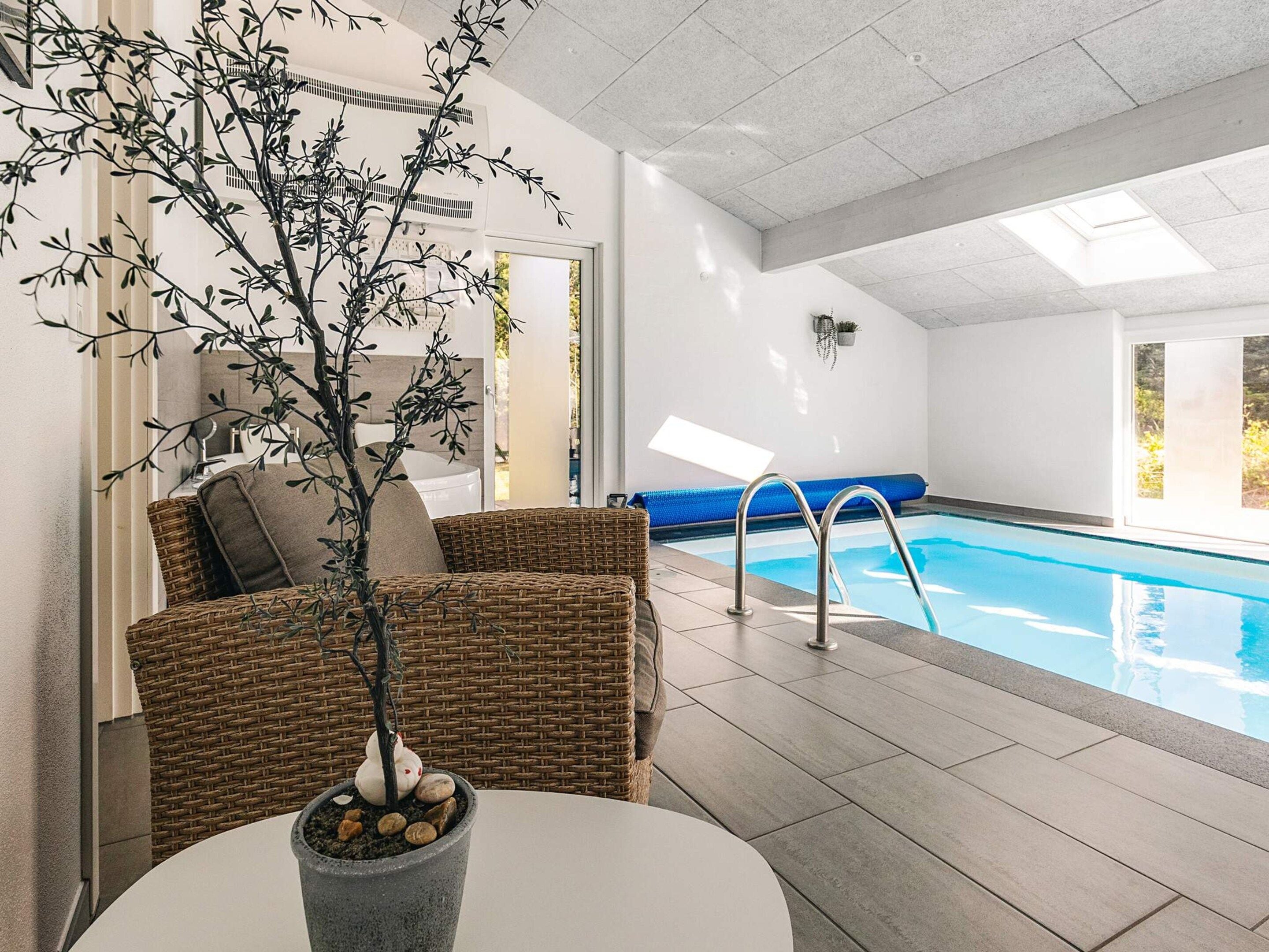 A poolside area with wicker furniture, a potted plant, and a clear view of the pool.