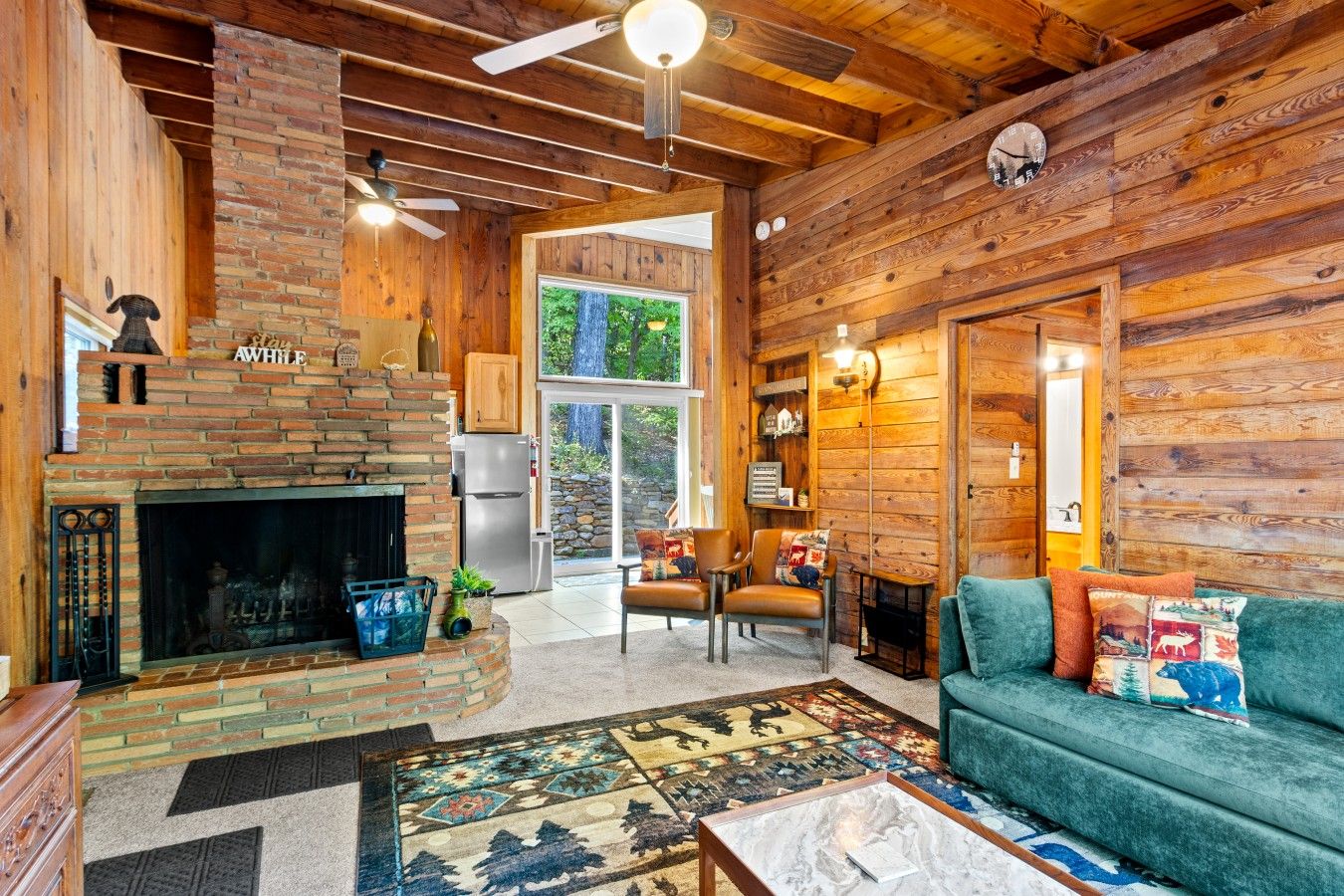 Un intérieur de chalet chaleureux avec une cheminée, des murs en bois, un canapé et un coin repas.