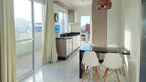 Een moderne keuken met een eethoek, grote ramen en uitzicht op de stad.