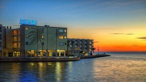 Ein Hotel mit der Aufschrift 'Sailport' am Wasser bei Sonnenuntergang.