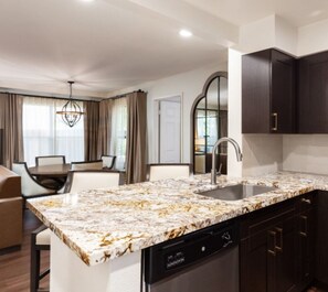 A modern kitchen with a marble countertop, a dishwasher, and dark cabinetry. - Two bedroom deluxe resort at West flamingo Bay resort Las Vegas (Las Vegas)