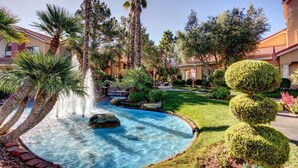 A landscaped pool area with palm trees, a fountain, and well-maintained bushes. - Two bedroom deluxe resort at West flamingo Bay resort Las Vegas (Las Vegas)