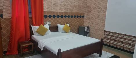 A room with a bed, a nightstand, a small table, and a wall with a patterned design.