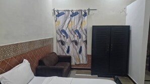 A bedroom with a bed, a sofa, a wardrobe, and a curtain with a bird pattern.