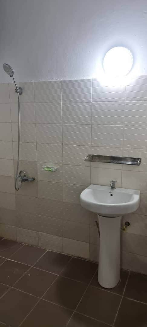 Un baño con ducha, lavamanos y un espejo redondo.