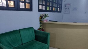A reception area with a green sofa, a small table, and a reception desk.