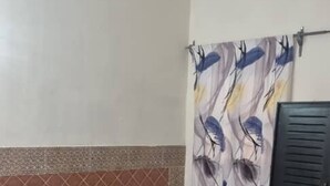 A hotel room with a bed, a sofa, a curtain with abstract patterns, and a black wardrobe.