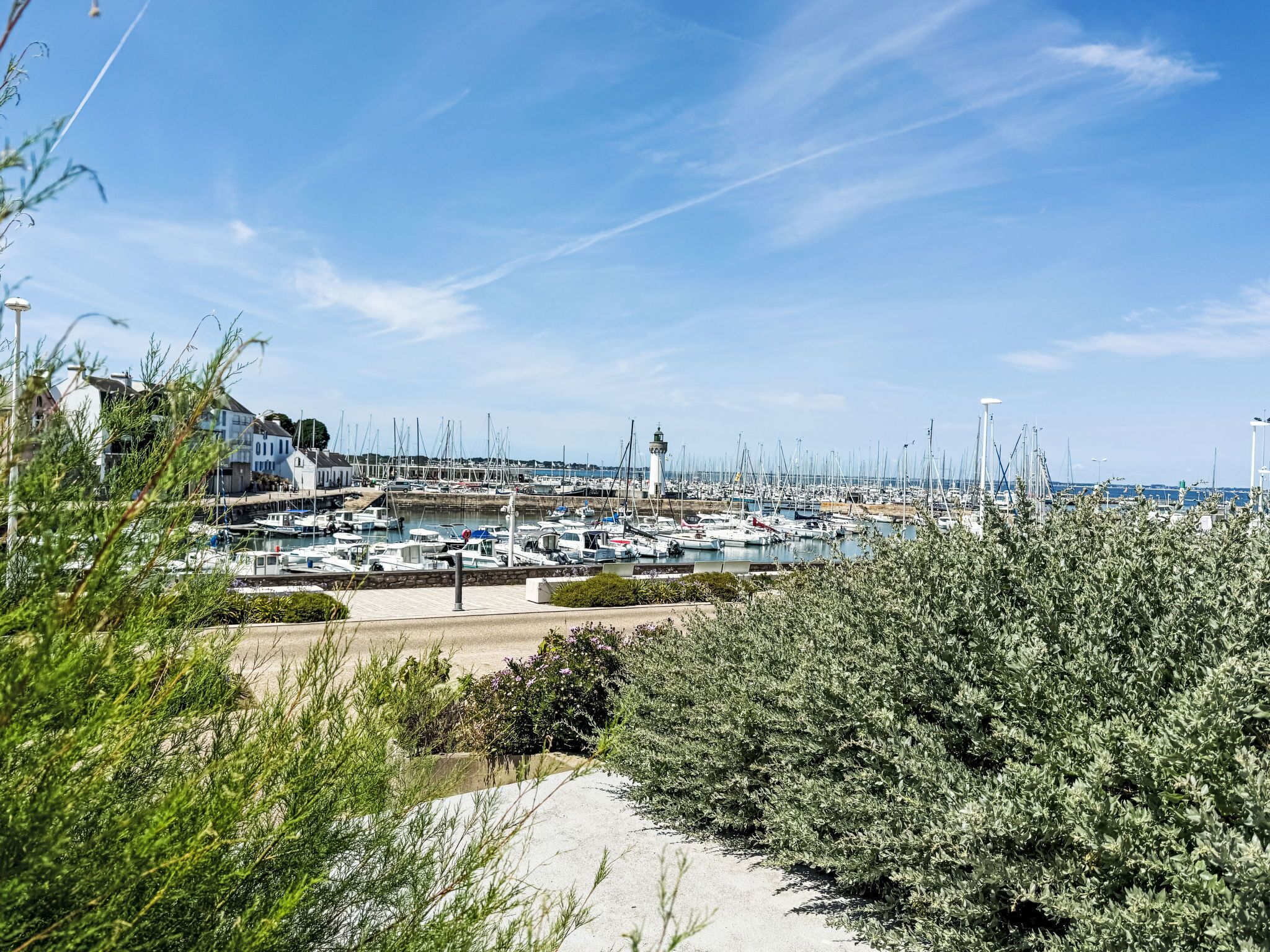 Un puerto deportivo con barcos, un faro y edificios al fondo.