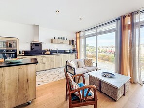 A modern kitchen with a dining area, large windows, and a view of the city. - Sombreuil by Interhome (Quiberon)