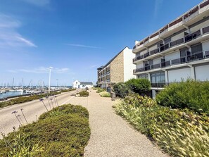 A coastal hotel with a paved walkway, a marina with boats, and a stone building with balconies. - Sombreuil by Interhome (Quiberon)