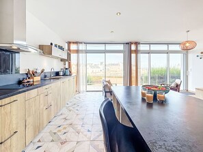 A modern kitchen with a large island, a dining area, and a view of the outside. - Sombreuil by Interhome (Quiberon)