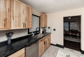 A kitchen with wooden cabinets, a black countertop, a stainless steel sink, and a dishwasher. - The Walnut Retreat~Whole house! Hot Tub~Library~ (Des Moines)