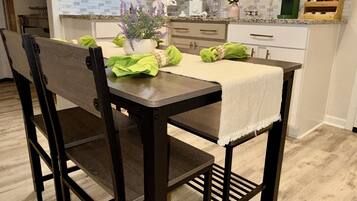 A modern kitchen with white cabinets, a dark wooden table, and chairs.